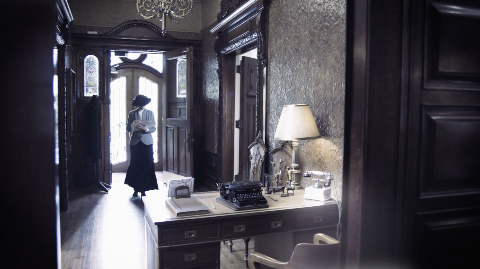 Évocation historique du documentaire Rodolphe Forget : Madame Francoeur, sténodactylo en costume du début des années 1900, entre dans le bureau de la maison de courtage L.J. Forget & Cie.